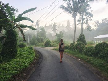 Rear view of woman walking on road