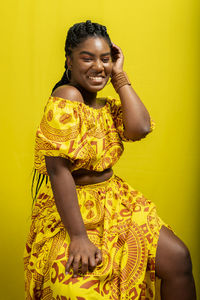 Young woman wearing colorful long clothes over yellow background. natural expression.