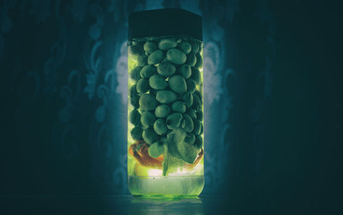 Digital composite image of glass jar on table against black background