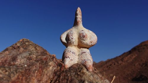 Low angle view of rock against clear blue sky