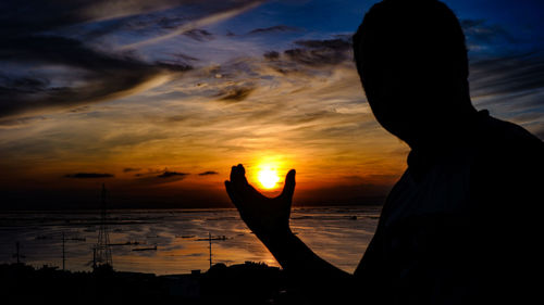 Silhouette woman by sea against sky during sunset