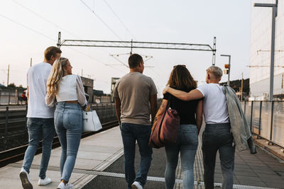 Rear view of people walking on railing