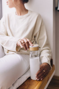 Black woman drinking water from a reusable water bottle