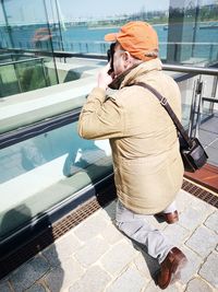 Rear view of man photographing through glass