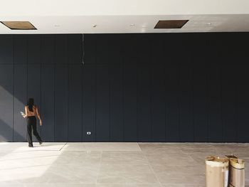 Full length of woman walking by black wall