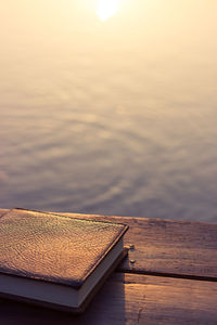 Open book on table against sky during sunset