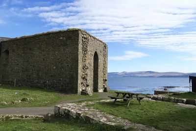 Old building by sea against sky