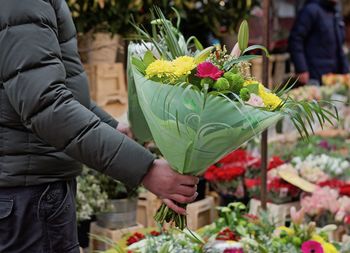 Midsection of woman with red roses in market