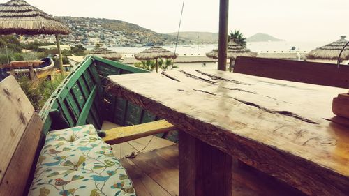 Chairs sitting on table by sea against mountain