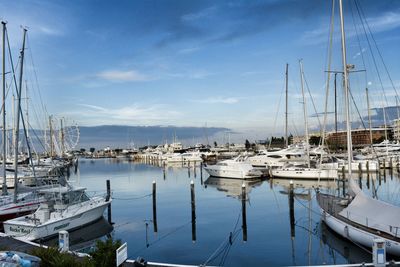 Boats moored at sea against cloudy sky