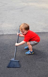 High angle view of boy cleaning road with broom