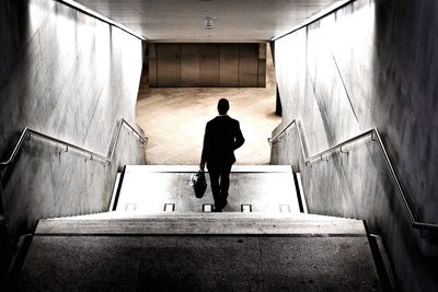 Rear view of man standing on staircase