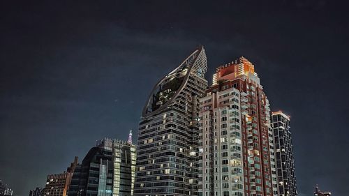 Low angle view of illuminated buildings against sky at night