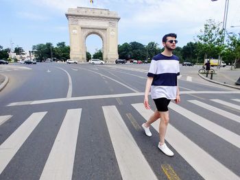 Full length of young man wearing sunglasses walking on road