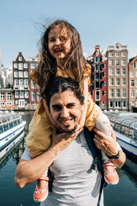 Portrait of friends standing at canal in city