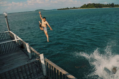 Man jumping in sea against sky