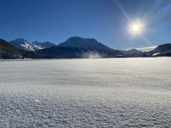 Scenic view of snow covered mountains against blue sky