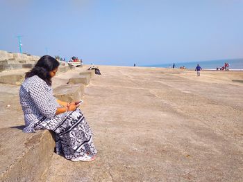 Woman on beach against clear sky