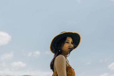 Portrait of young woman standing against sky