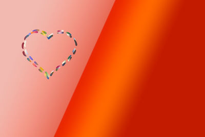 Close-up of heart shape against orange background