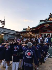 Rear view of people outside temple against sky