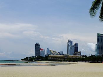 Sea by modern buildings against sky