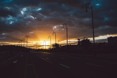 Cars on street against sky during sunset