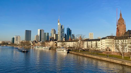 View of buildings by river against sky in city