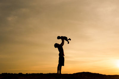 Silhouette men standing against sky during sunset