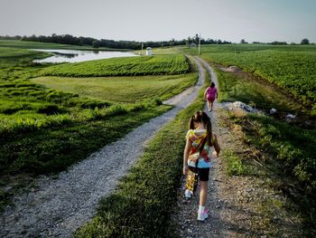 Rear view of girl standing on field against sky