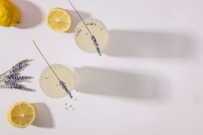 Still life with lavender infused lemonade and lemons on the white table with long shadows, top view