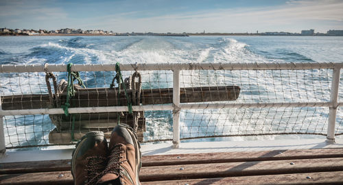 Low section of woman in swimming pool by sea against sky