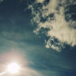 Low angle view of sun shining through clouds