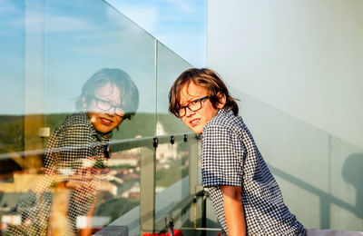 Rear view of a boy and his  reflection in glass
