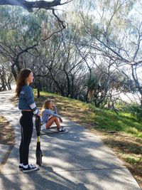 Rear view of mother and daughter sitting on road