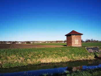 Built structure on field against clear blue sky