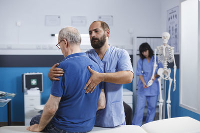 Side view of young man using mobile phone while sitting in hospital