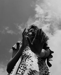 Low angle view of woman holding cigarette against sky