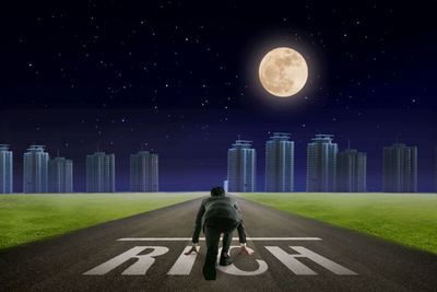 Rear view of businessman standing on rich text against sky at night
