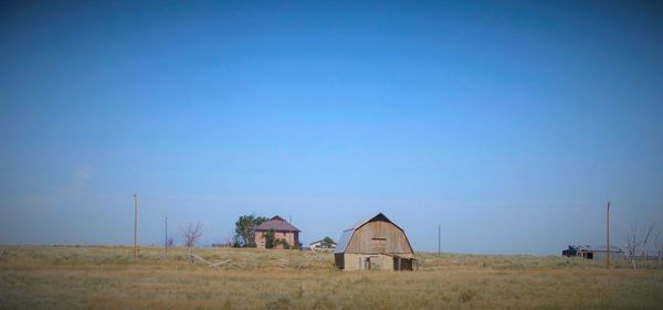 Houses on field against clear blue sky