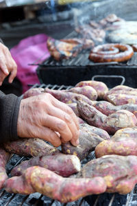 Cropped hands of person preparing food on barbecue grill