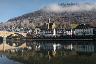 Buildings by lake against sky