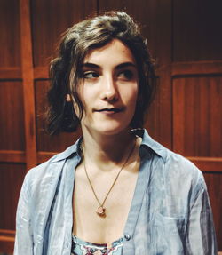 Portrait of young woman standing against wall
