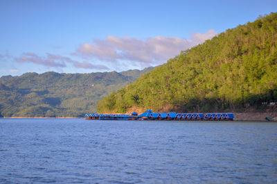 Scenic view of river by tree mountains against sky