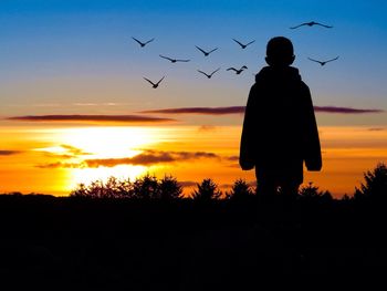 Silhouette people standing on landscape at sunset