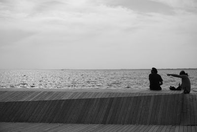 People sitting on beach against sky