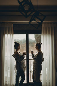 Woman standing by window at home