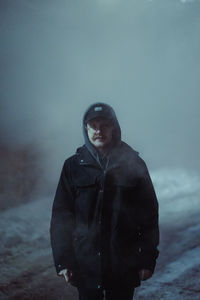 Portrait of young man standing against snow