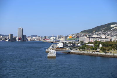 View of sea and buildings against clear blue sky