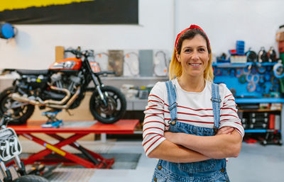 Portrait of mechanic woman standing on motorcycle factory